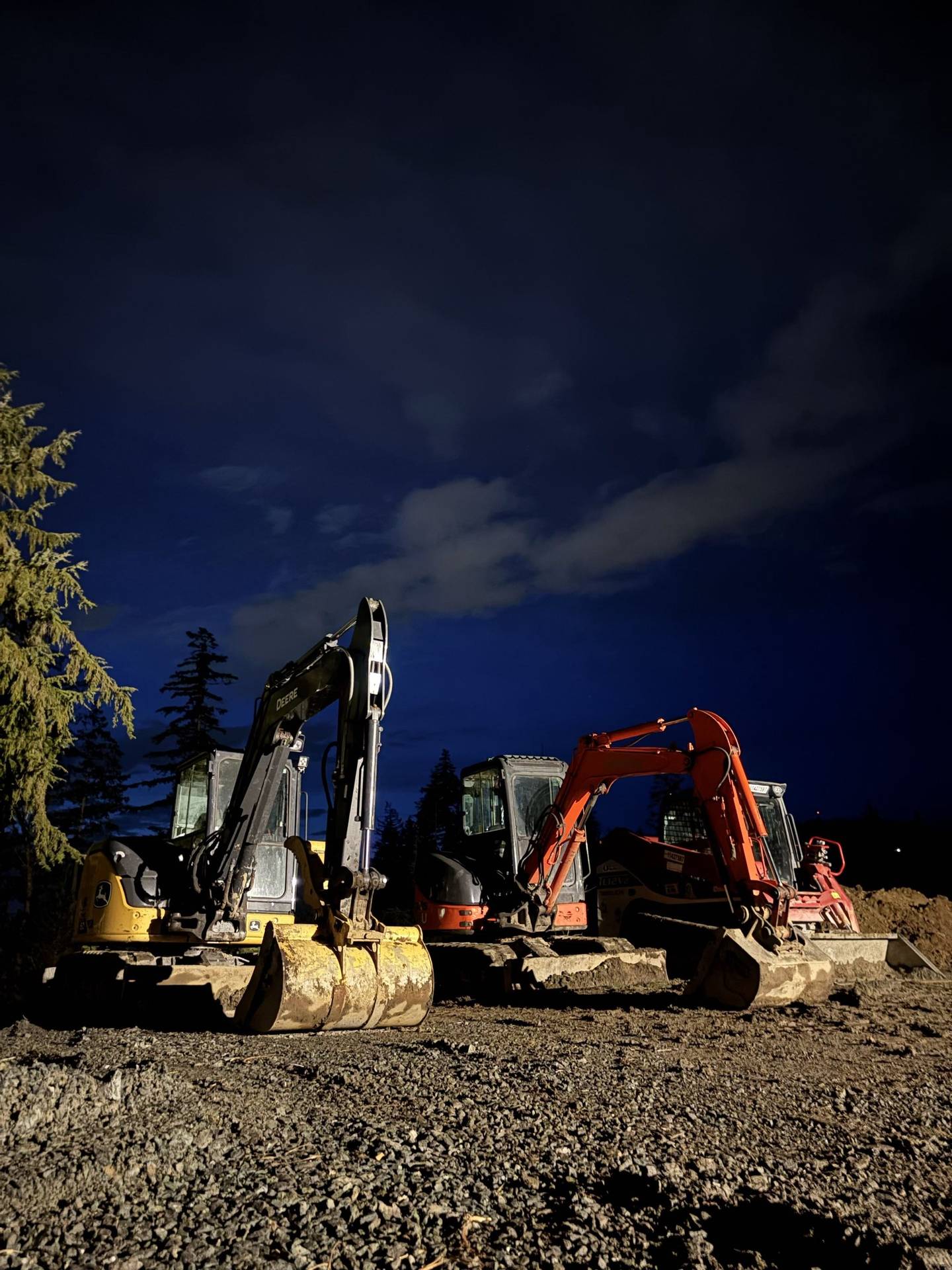 Two JMEX machines parked on a job site at dusk, the valley behind them